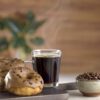 Donuts com cobertura de cafe sendo servido ao lado de uma xicara de cafe
